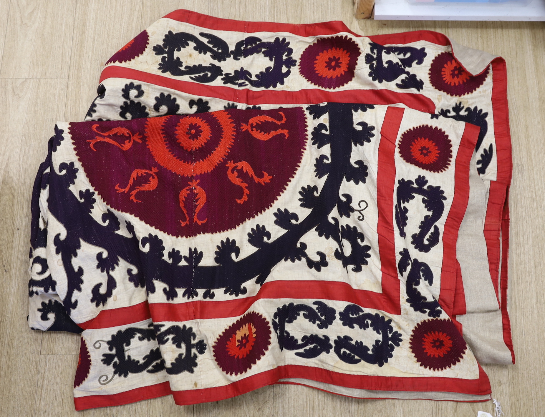 A Suzani hanging, embroidered with two rows of red and aubergine roundels, 274 x 248cm
